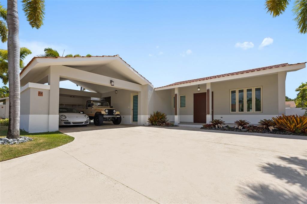A single-story house with a carport, a driveway, and palm trees under a blue sky — 112 CAMINO DE LOS LOTOS, DORADO, PR