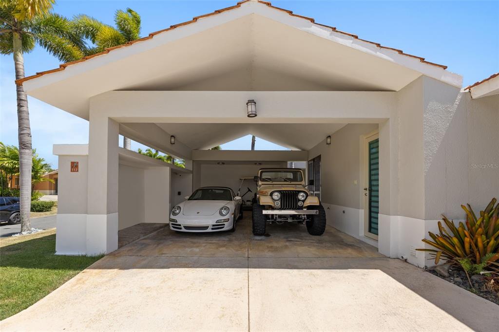 A covered carport features a white sports car and a tan off-road vehicle parked inside — 112 CAMINO DE LOS LOTOS, DORADO, PR