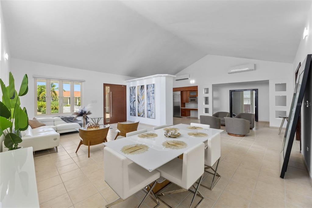 A bright, open-concept living and dining area features white tile floors and vaulted ceilings — 112 CAMINO DE LOS LOTOS, DORADO, PR