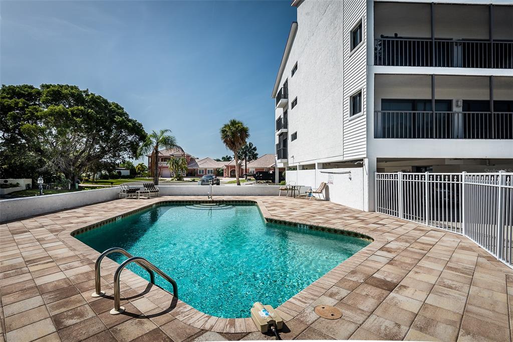 An outdoor swimming pool with a metal ladder sits on a paved patio beside a building — 1801 JAMAICA WAY UNIT 331, PUNTA GORDA, FL