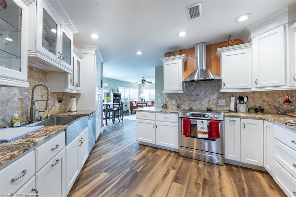 A kitchen features white cabinets, stainless steel appliances, granite countertops, and wood-look flooring — 1801 JAMAICA WAY UNIT 331, PUNTA GORDA, FL