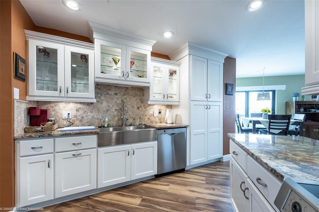 A kitchen features white cabinets, a stainless steel farmhouse sink, and granite countertops — 1801 JAMAICA WAY UNIT 331, PUNTA GORDA, FL