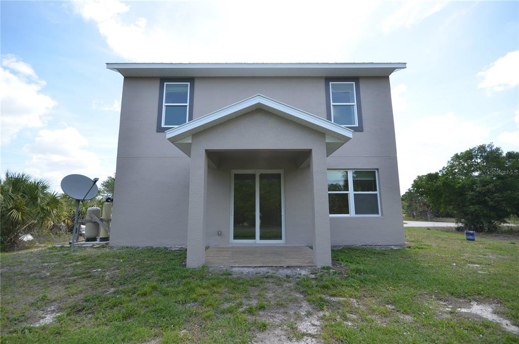 The exterior rear view of a two-story house with a covered patio and sliding doors — 272 PELTON CIRCLE, PORT CHARLOTTE, FL