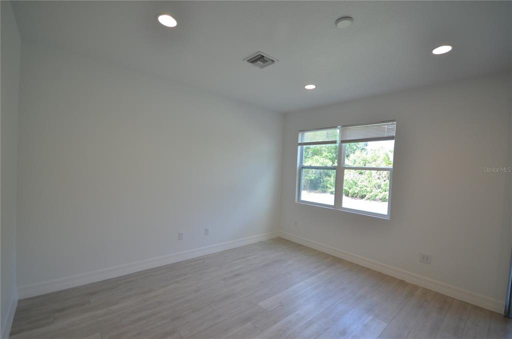 An empty bedroom features white walls, light wood-look flooring, recessed lighting, and a single window — 272 PELTON CIRCLE, PORT CHARLOTTE, FL