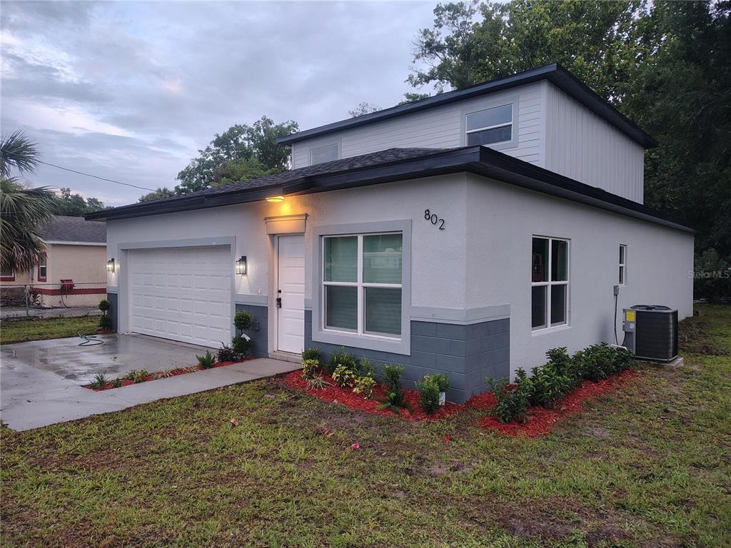 A two-story house with a white stucco exterior, gray block accents, and a garage — 802 MARVIN C ZANDERS AVENUE, APOPKA, FL