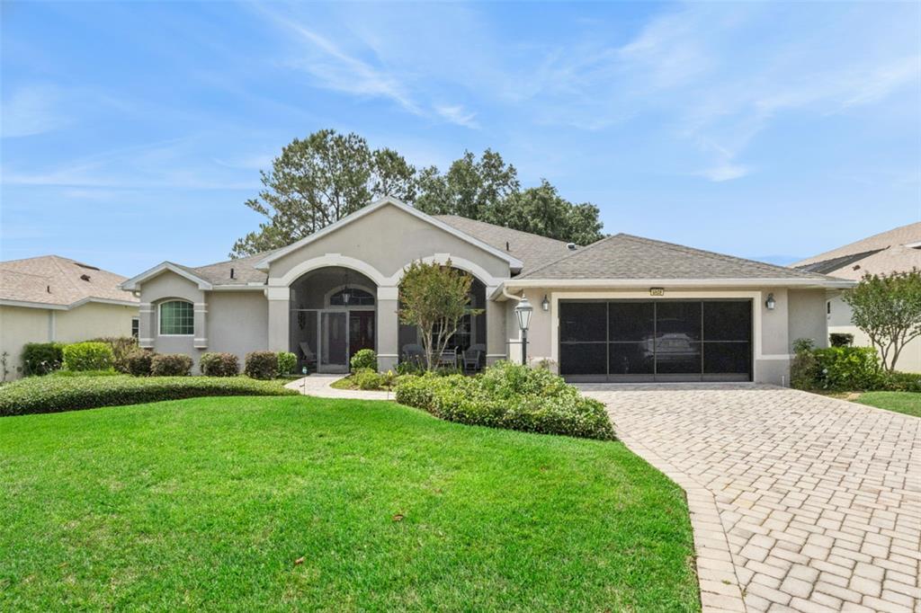 A single-story house with a paved driveway, a two-car garage, and a covered front entryway — 5607 SIR CHURCHILL DRIVE, LEESBURG, FL