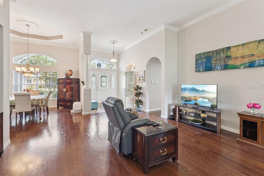 A living room with hardwood floors, a recliner, a television, and an adjacent dining area — 5607 SIR CHURCHILL DRIVE, LEESBURG, FL