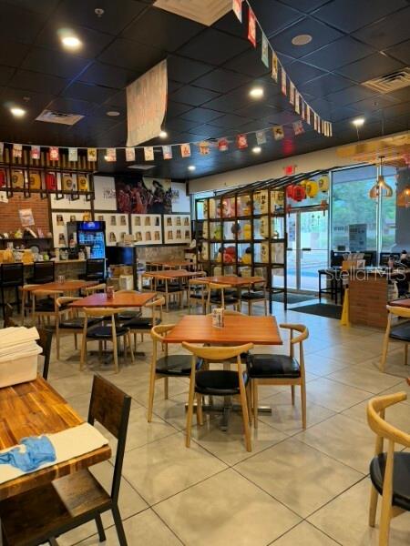 A restaurant dining room features wooden tables, black chairs, and decorative banners hanging from the ceiling — TBA NW 43RD STREET, GAINESVILLE, FL