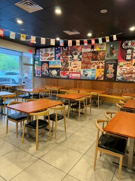 A restaurant dining area features wooden tables, black chairs, and a wall covered in posters — TBA NW 43RD STREET, GAINESVILLE, FL