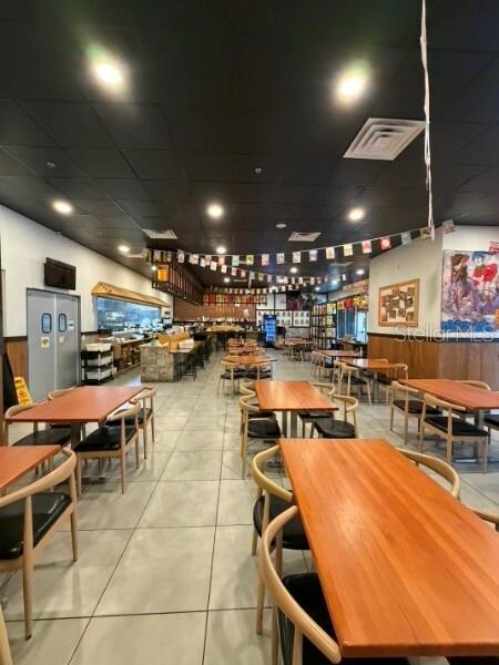 The interior of a restaurant features rows of wooden tables and chairs under a dark ceiling — TBA NW 43RD STREET, GAINESVILLE, FL