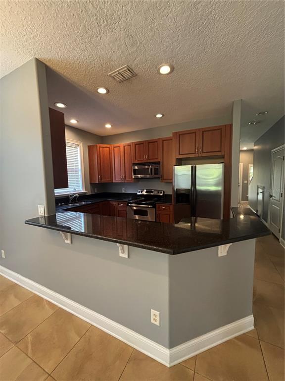 A kitchen with wood cabinets, stainless steel appliances, and a dark granite breakfast bar — 2505 KILGORE STREET, ORLANDO, FL