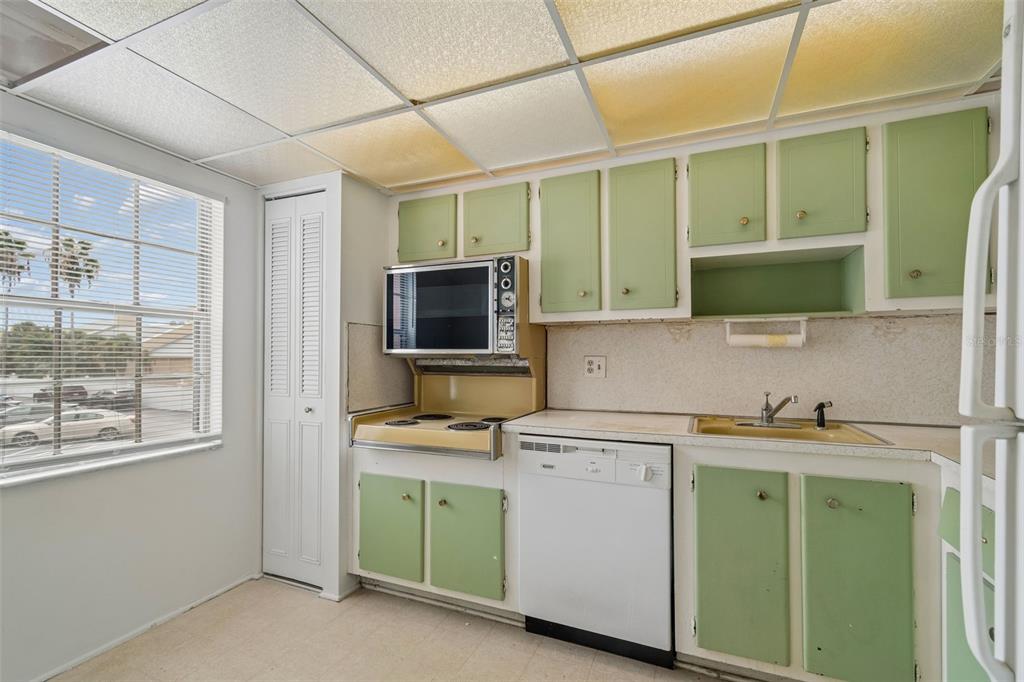 A kitchen features light green cabinets, a drop-in stove, a dishwasher, and a drop ceiling — 1900 68TH STREET N UNIT 210, ST PETERSBURG, FL