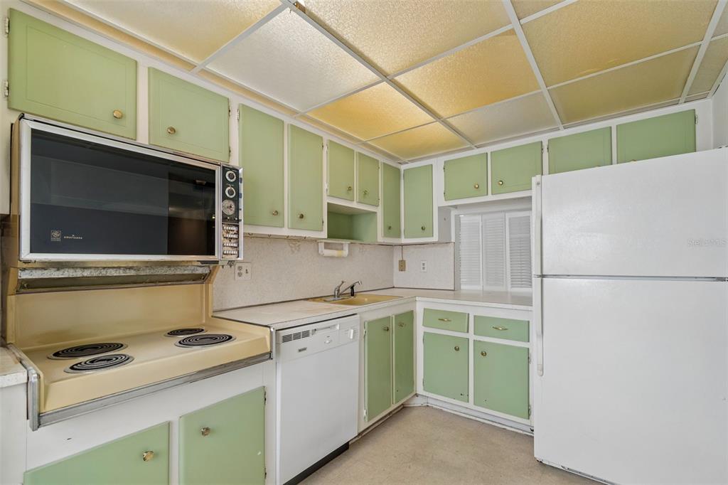 A kitchen features vintage light green cabinets, a yellow sink, and a drop ceiling — 1900 68TH STREET N UNIT 210, ST PETERSBURG, FL