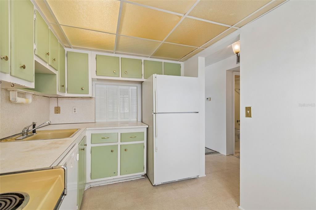 A kitchen features light green cabinets, a white refrigerator, and a yellow drop ceiling — 1900 68TH STREET N UNIT 210, ST PETERSBURG, FL