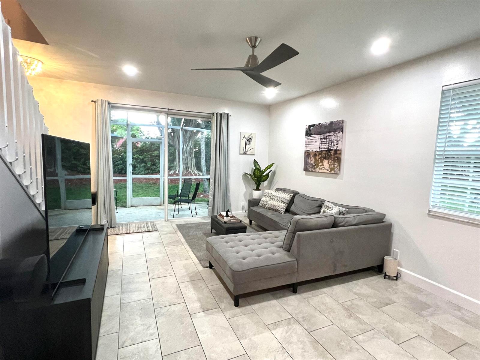 A living room features a grey sectional sofa, tile flooring, a ceiling fan, and sliding doors — 2046 Madeira Drive, Weston FL 33327, WESTON, FL