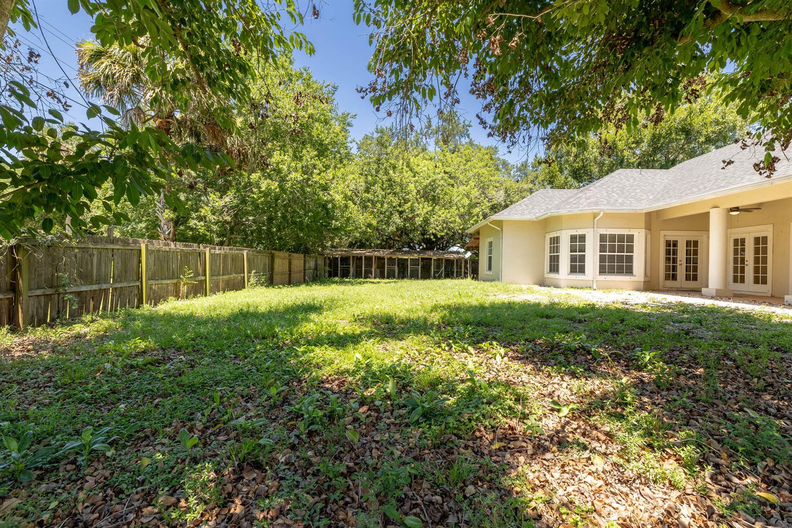 A backyard features a grassy lawn, a wooden fence, and the rear of a house — 2306 NW 4th Street, Okeechobee FL 34972, OKEECHOBEE, FL