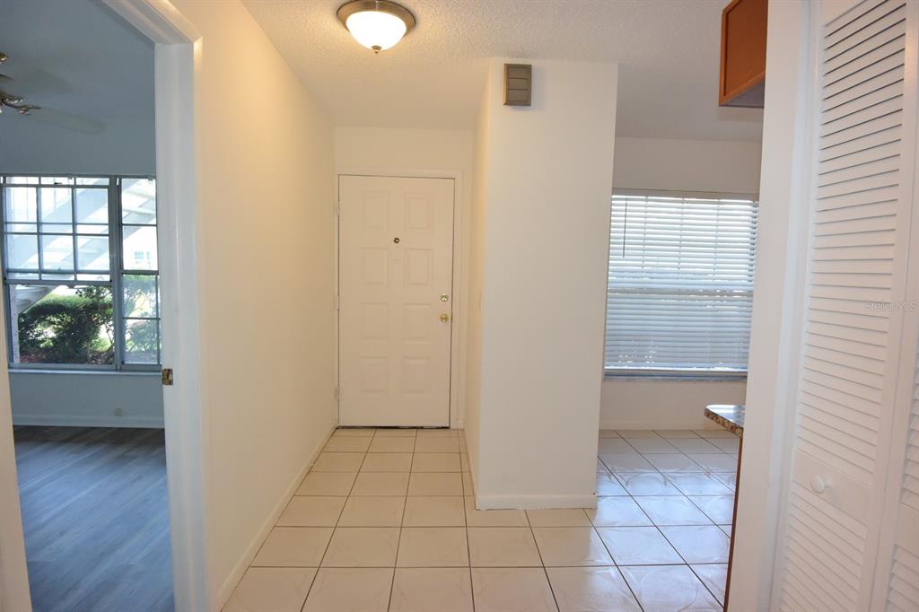 An entryway with tiled flooring leads to a white front door and an adjacent room — 4908 MYRTLE OAK DRIVE UNIT 12, NEW PORT RICHEY, FL