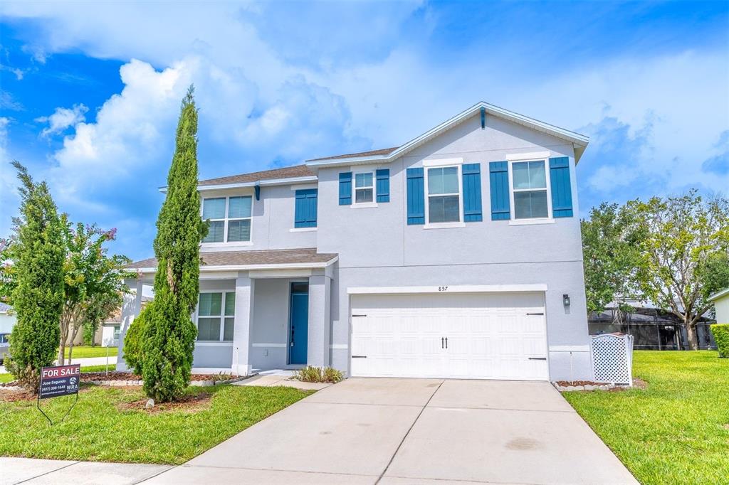 A two-story house with a light gray exterior, blue shutters, and a two-car garage — 857 SHEEN CIRCLE, HAINES CITY, FL