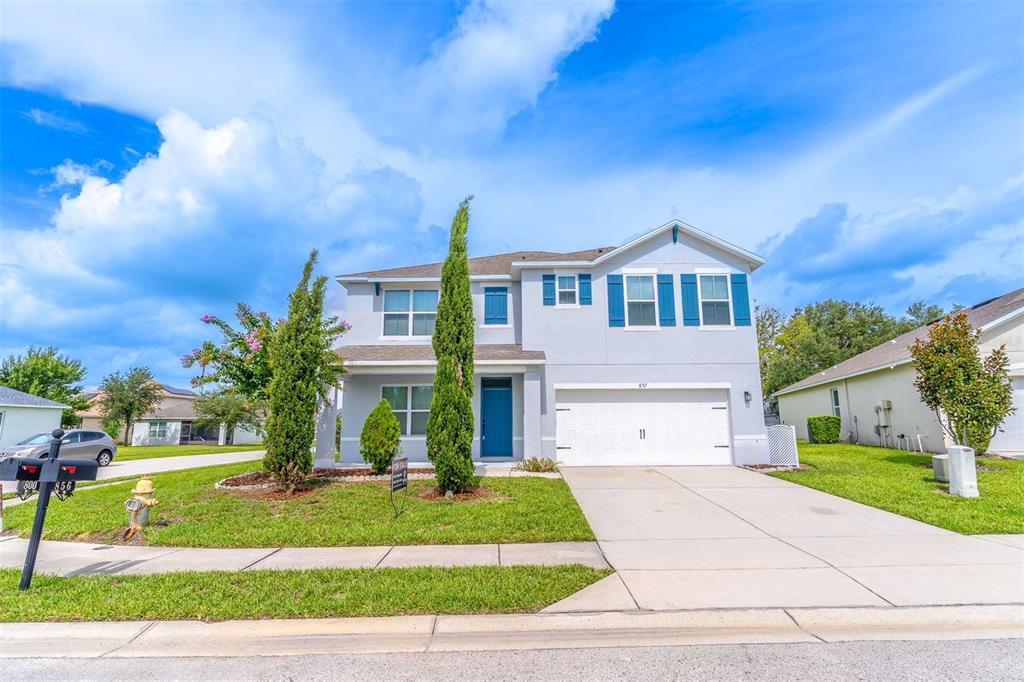 A two-story suburban house with a blue front door, white garage, and green lawn — 857 SHEEN CIRCLE, HAINES CITY, FL