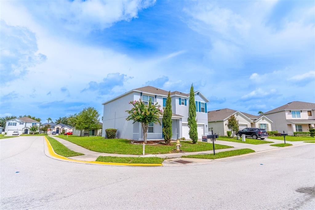 A two-story suburban house sits on a corner lot under a blue sky — 857 SHEEN CIRCLE, HAINES CITY, FL