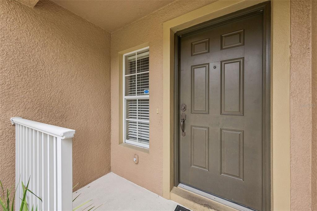 A brown front door with a window and white railing on a covered porch — 4246 TRIDENT POINT, OVIEDO, FL