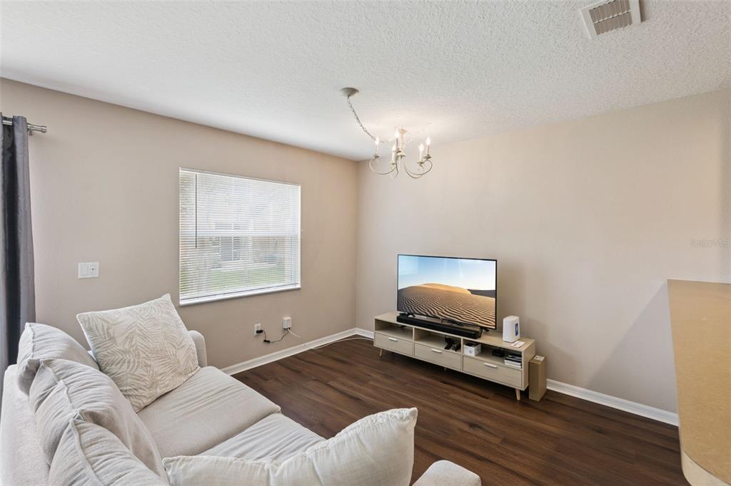 A living room features a beige sofa, a television on a media console, and wood flooring — 4246 TRIDENT POINT, OVIEDO, FL