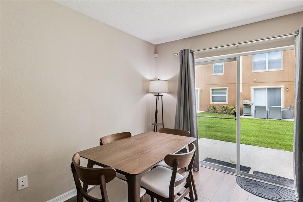 A dining area features a wooden table, four chairs, a floor lamp, and sliding glass doors — 4246 TRIDENT POINT, OVIEDO, FL