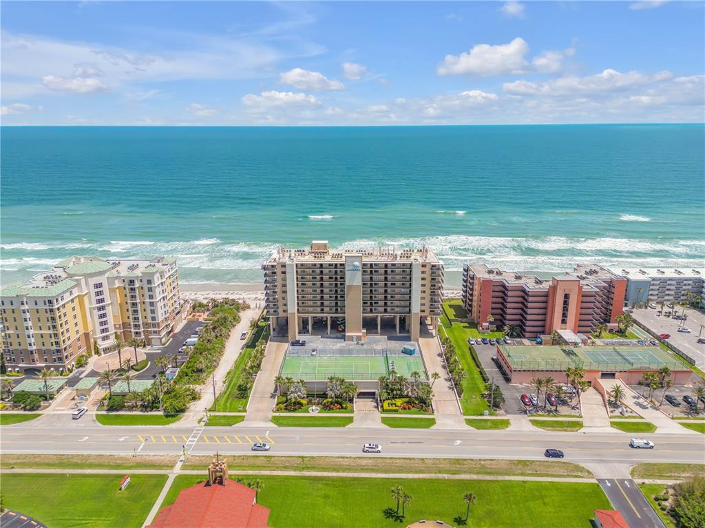 An aerial view of a beachfront condominium complex with tennis courts and a parking lot — 4139 S ATLANTIC AVENUE UNIT B707, NEW SMYRNA BEACH, FL