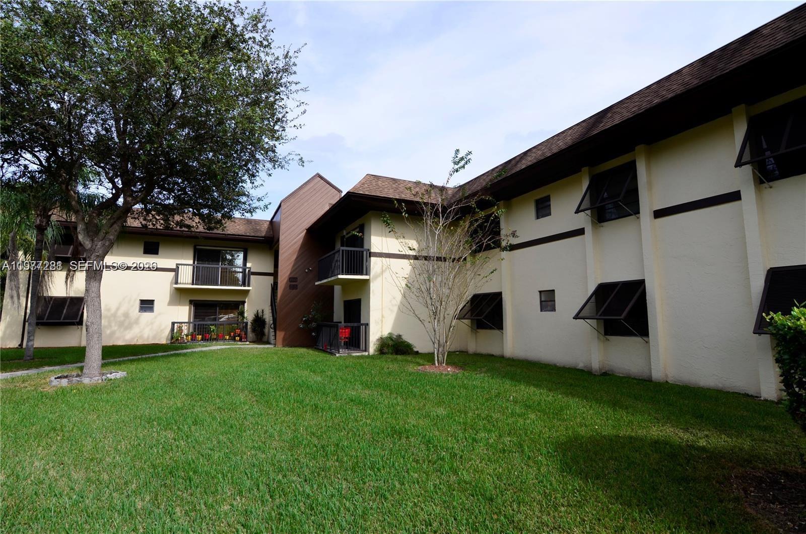 A multi-story apartment building with beige stucco walls, brown trim, and a grassy lawn — 7985 SW 86th St # 432, Miami FL 33143, MIAMI, FL
