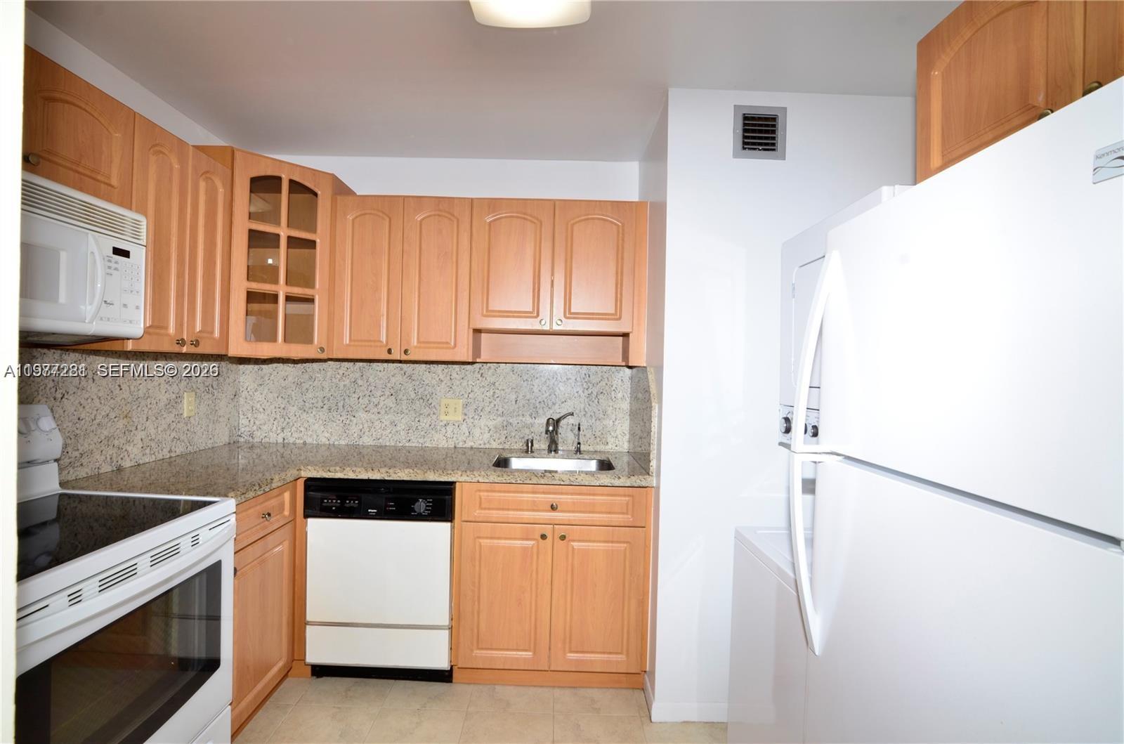 A kitchen features light wood cabinets, granite countertops, white appliances, and a stainless steel sink — 7985 SW 86th St # 432, Miami FL 33143, MIAMI, FL