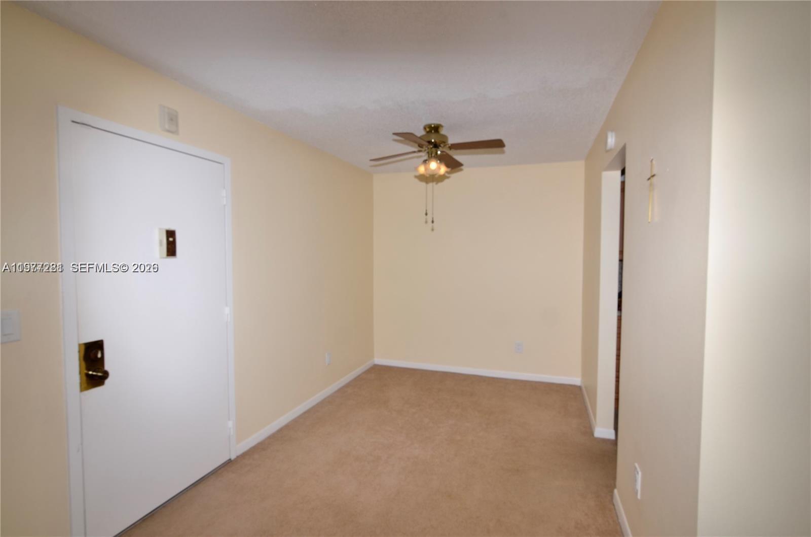 An empty room features beige walls, tan carpeting, and a ceiling fan with lights — 7985 SW 86th St # 432, Miami FL 33143, MIAMI, FL
