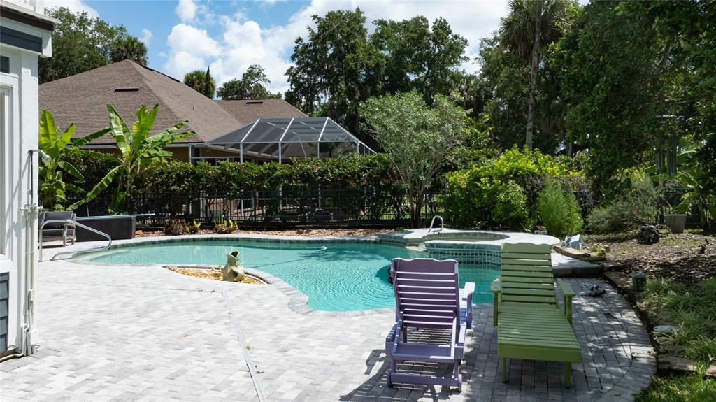 A backyard features a swimming pool with a spa, patio furniture, and lush landscaping — 6315 PALMAS BAY CIRCLE, PORT ORANGE, FL