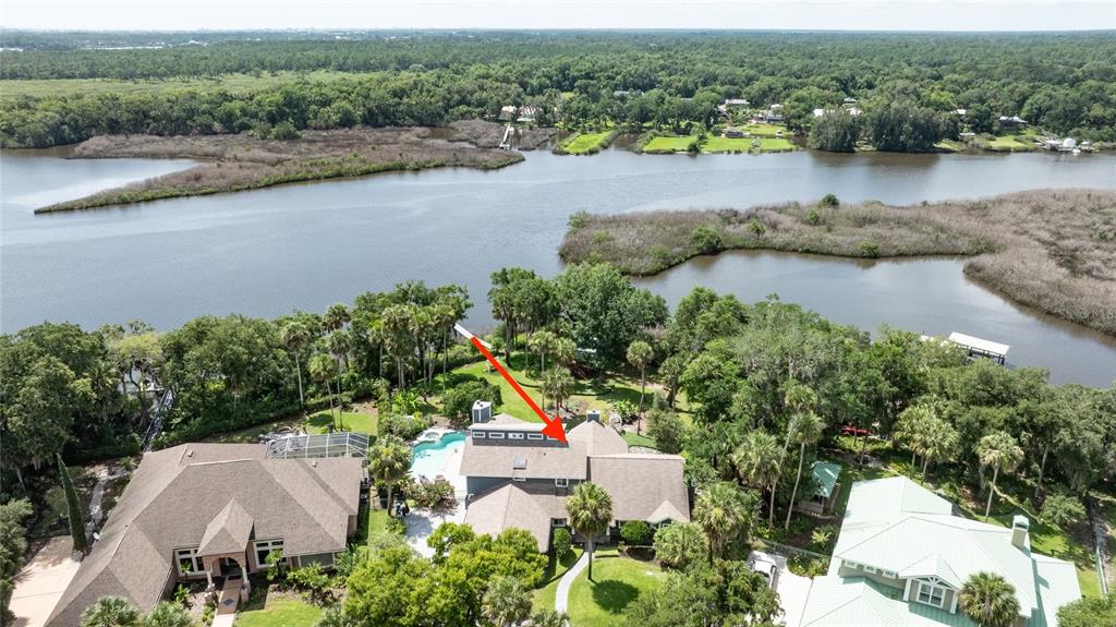 An aerial view shows a large house with a pool near a river and trees — 6315 PALMAS BAY CIRCLE, PORT ORANGE, FL