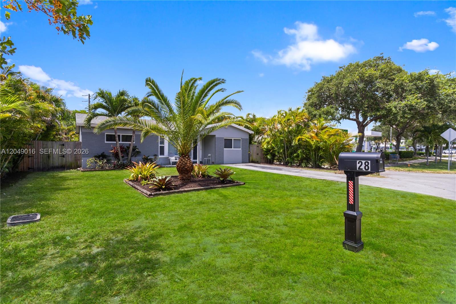 A grey single-story house features a palm tree in the front yard and a mailbox — 28 SE 7th St, Dania Beach FL 33004, DANIA BEACH, FL