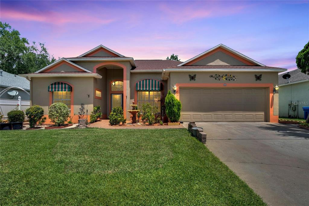 A single-story house with a two-car garage, a front fountain, and green striped window awnings — 813 INNERGARY PLACE, VALRICO, FL