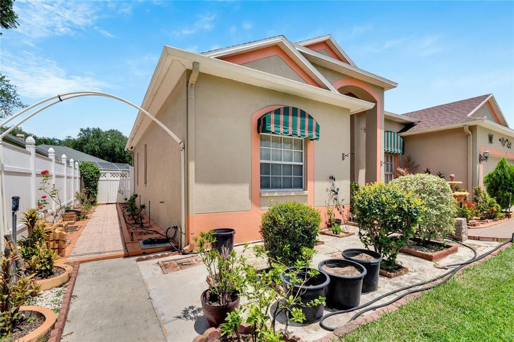 A beige house with orange trim features a green-striped awning over a front window — 813 INNERGARY PLACE, VALRICO, FL