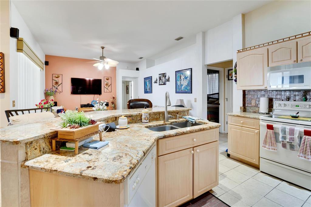 A kitchen with granite countertops, light wood cabinets, and a breakfast bar overlooking the living room — 813 INNERGARY PLACE, VALRICO, FL