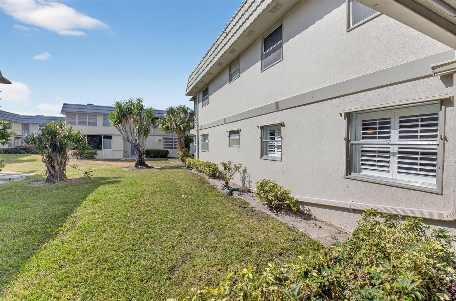 A side view of a two-story apartment building with a grassy lawn and landscaping — 61 Brittany B # 61, Delray Beach FL 33446, DELRAY BEACH, FL