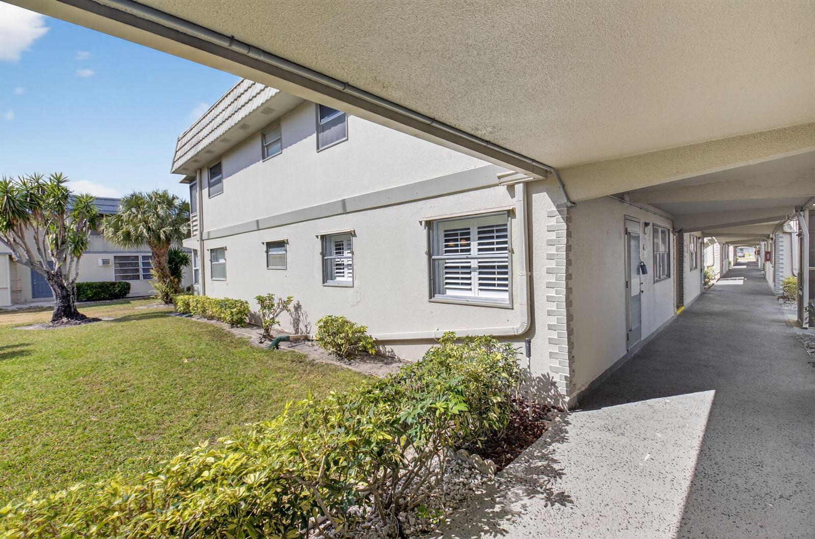 An exterior view of a two-story apartment building with a covered walkway and landscaping — 61 Brittany B # 61, Delray Beach FL 33446, DELRAY BEACH, FL