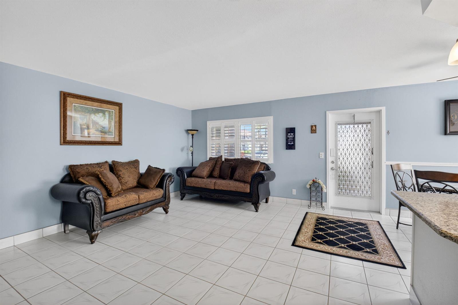 A living room features light blue walls, white tile flooring, and two dark-toned sofas — 61 Brittany B # 61, Delray Beach FL 33446, DELRAY BEACH, FL