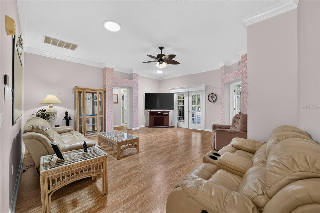 A living room features light-colored walls, wood-look flooring, two leather sofas, and a glass-topped coffee table — 1230 DESILVA STREET, THE VILLAGES, FL