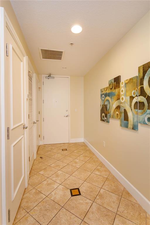A tiled entryway features a white door, louvered closet doors, and abstract wall art — 101 S EOLA DRIVE UNIT 1021, ORLANDO, FL
