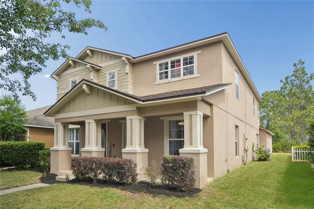 A two-story house with a tan stucco exterior, a covered front porch, and a grassy yard — 13619 PHOENIX DRIVE, ORLANDO, FL