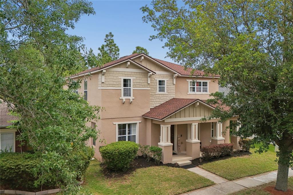 A two-story suburban house with a tan stucco exterior, shingled roof, and a front porch — 13619 PHOENIX DRIVE, ORLANDO, FL