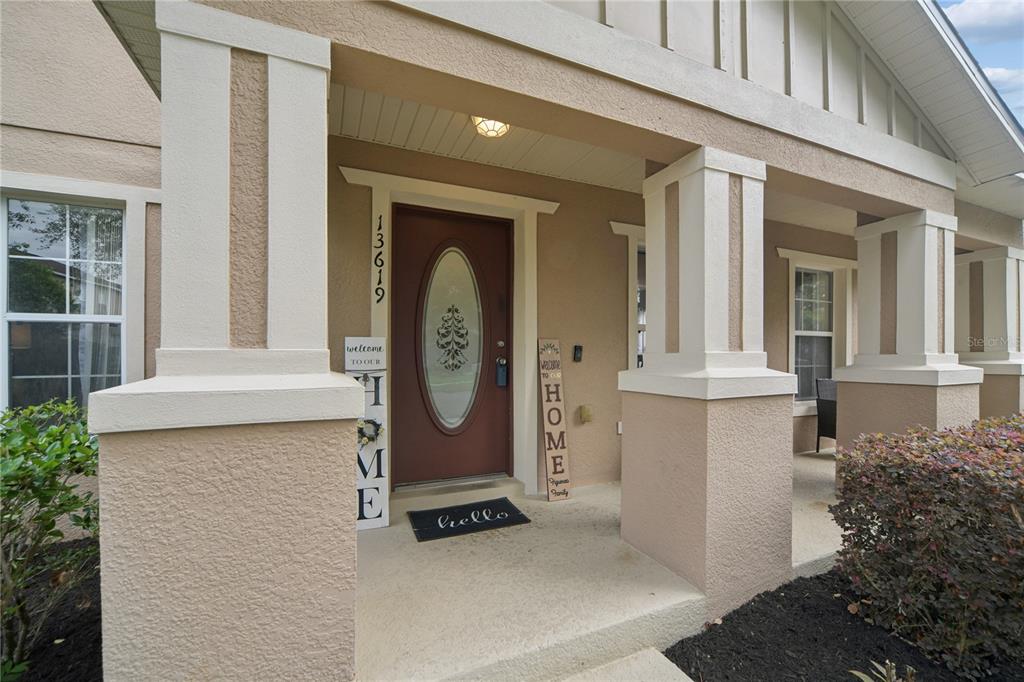 A covered front porch features a brown door with an oval window and two welcome signs — 13619 PHOENIX DRIVE, ORLANDO, FL