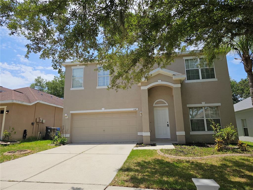 A two-story beige house with a two-car garage and a front entrance under an archway — 1147 EMERALD HILL WAY, VALRICO, FL