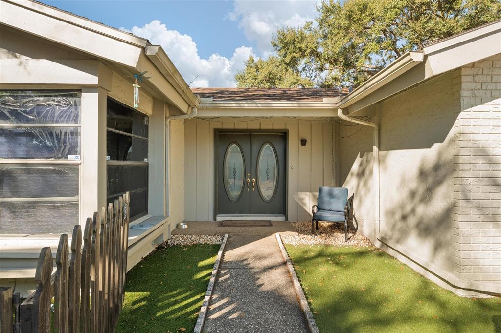A concrete walkway leads to the double front doors of a house with beige siding — 15648 BEAR CREEK DRIVE, TAMPA, FL
