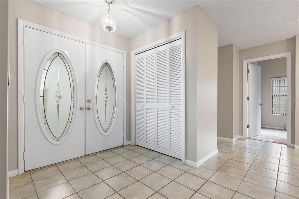 An entryway features white double doors with oval glass inserts, a louvered closet, and tile flooring — 15648 BEAR CREEK DRIVE, TAMPA, FL