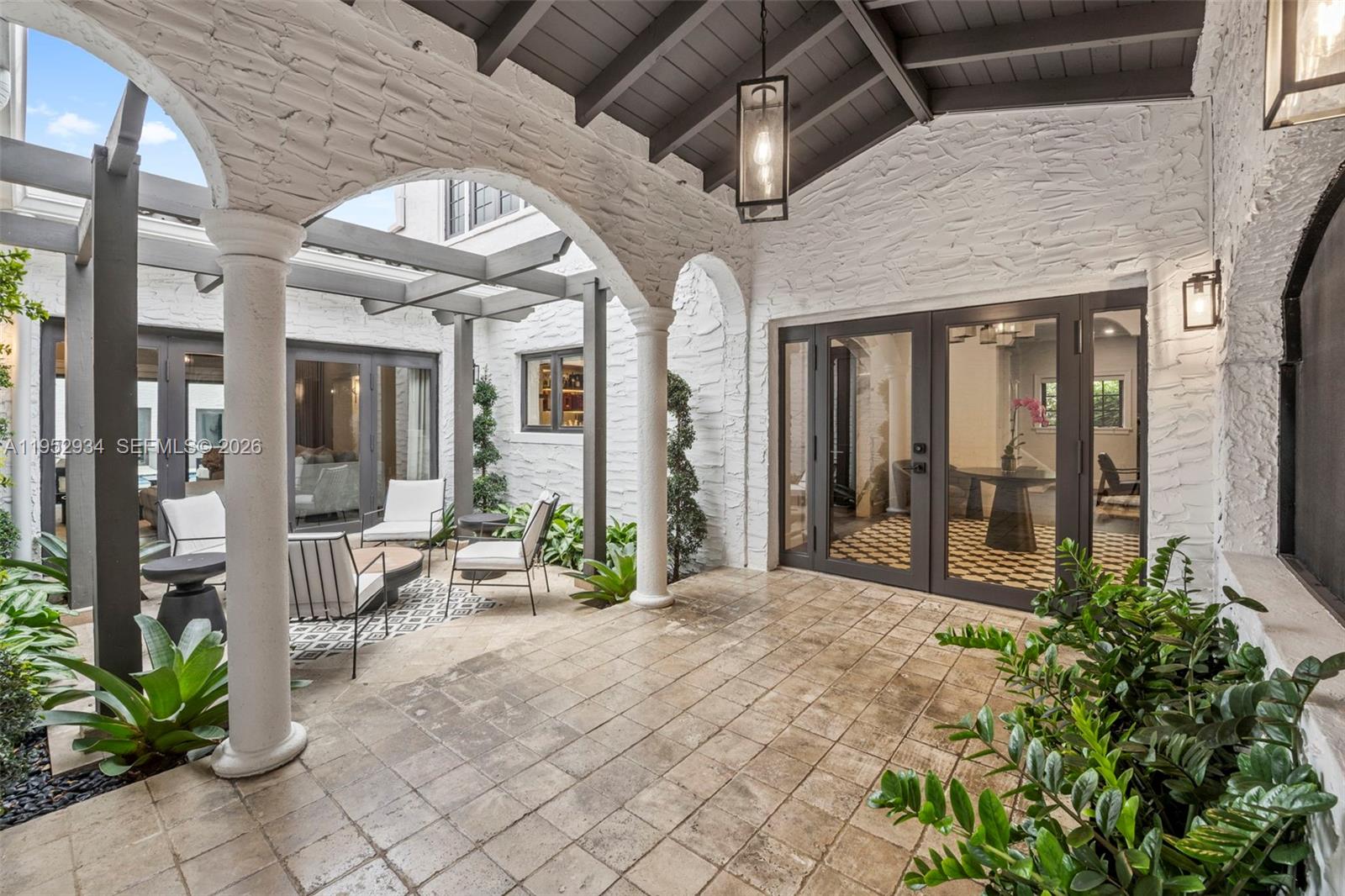 A covered outdoor patio features white brick walls, arched columns, and a tiled floor — 1236 Obispo Ave, Coral Gables FL 33134, CORAL GABLES, FL