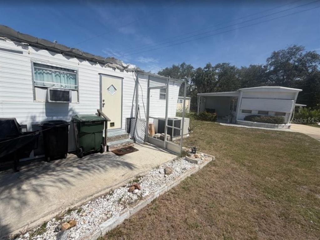 The exterior of a mobile home features white siding, a concrete patio, and a carport — 90 SOUTHWINDS DRIVE, SARASOTA, FL
